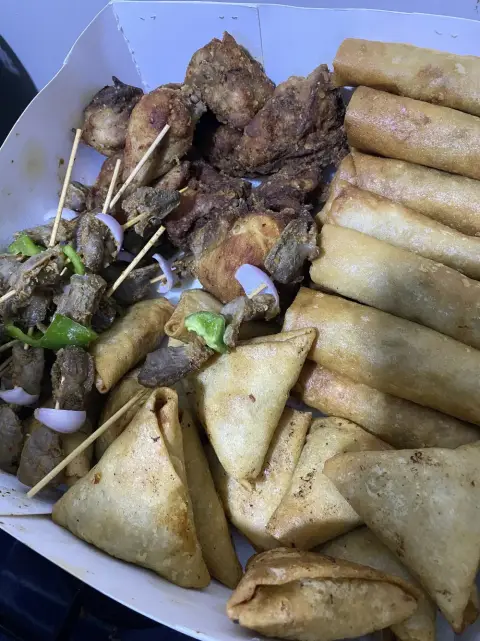 A party box of Nigerian small chops: samosas, spring rolls and peppered chicken