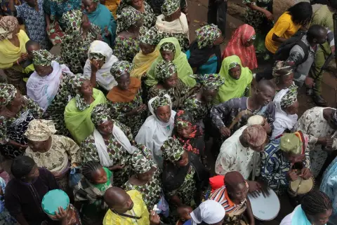 Guests in matching aso-ebi fabric and gele walking together to a celebration in Nigeria